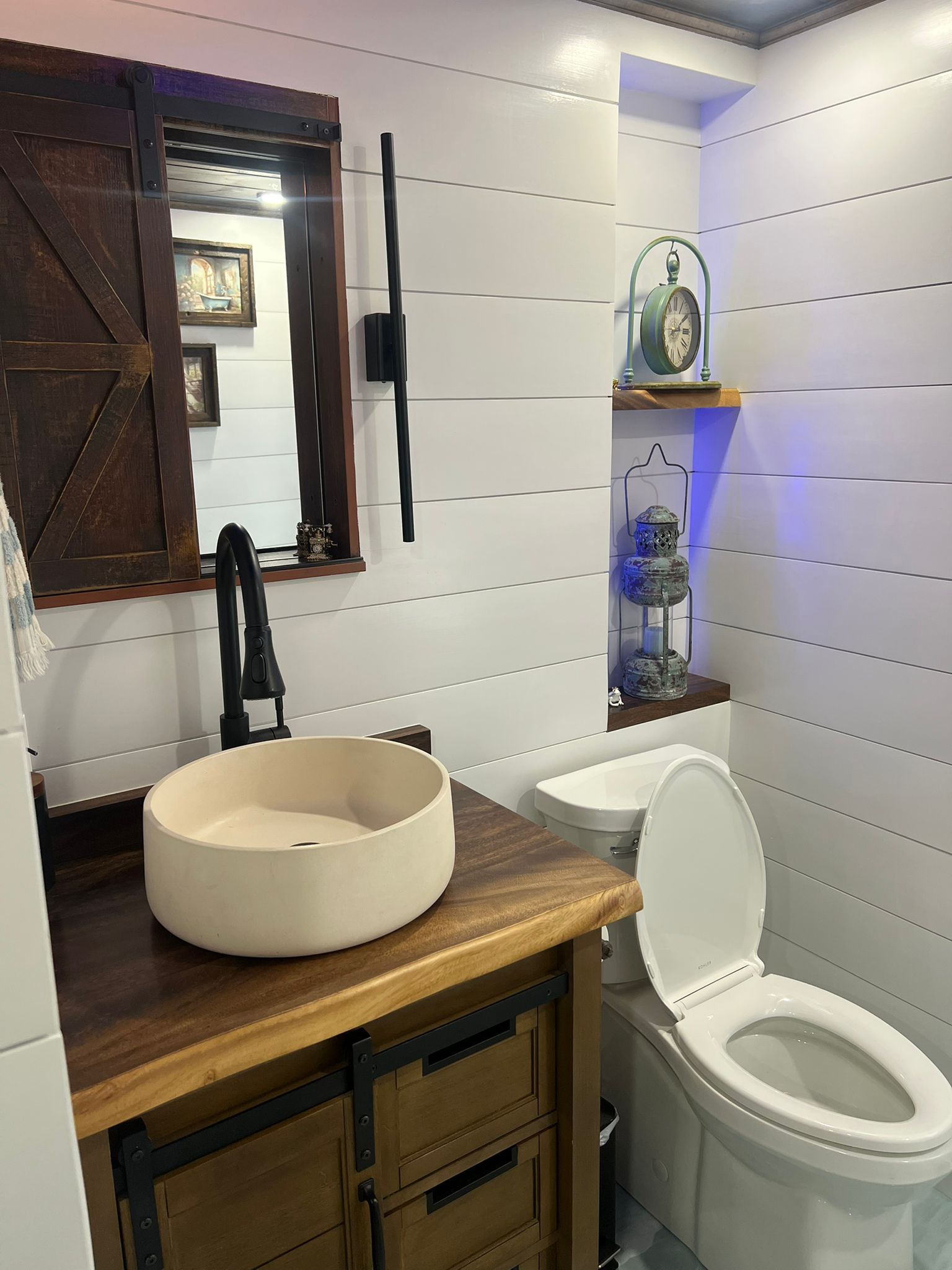 Bathroom vanity detail with vessel sink, black faucet, wood top and sliding mirror